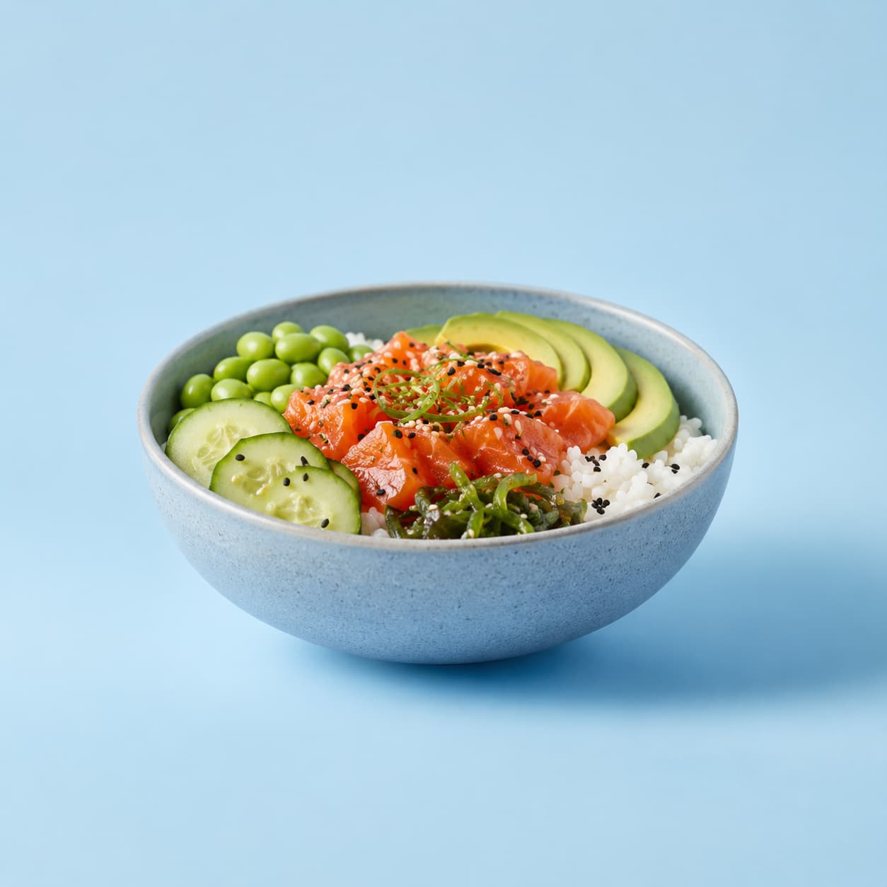 Poke bowl photographed against a pastel blue studio background